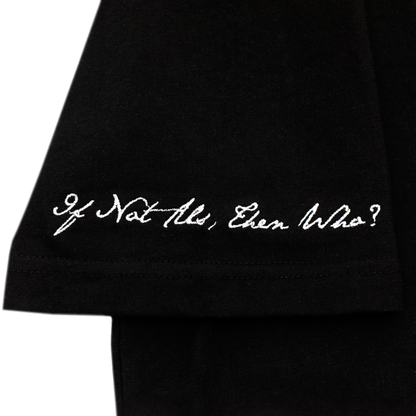 Arm close up view of a black tee with refined embroidery detail on the sleeve and screen-printed details on the front and back, this tee delivers a balance of comfort, structure, and everyday wearability.